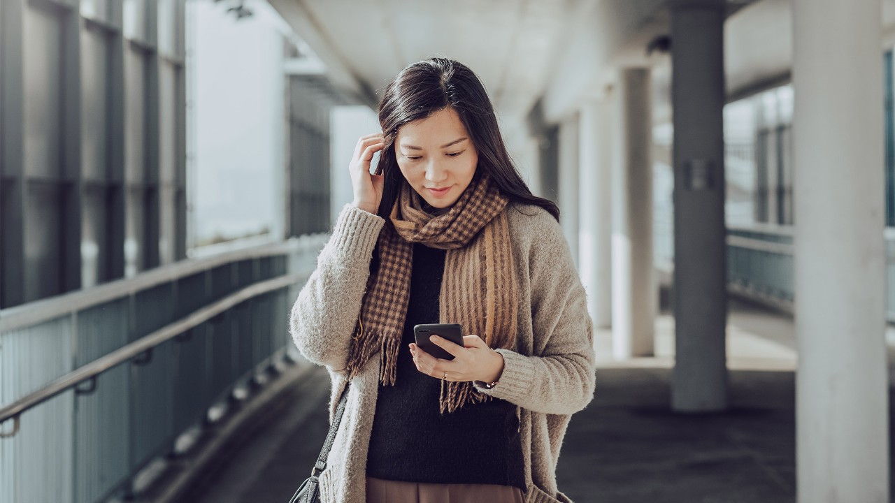 A woman is looking at her mobile phone; image used for "manage existing debt" article.