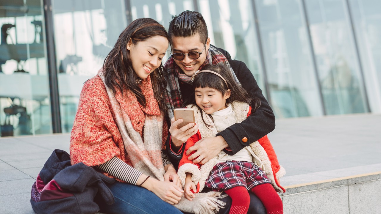 A little girl and her parents are looking at the mobile happily; image used for "protect what matters" article.