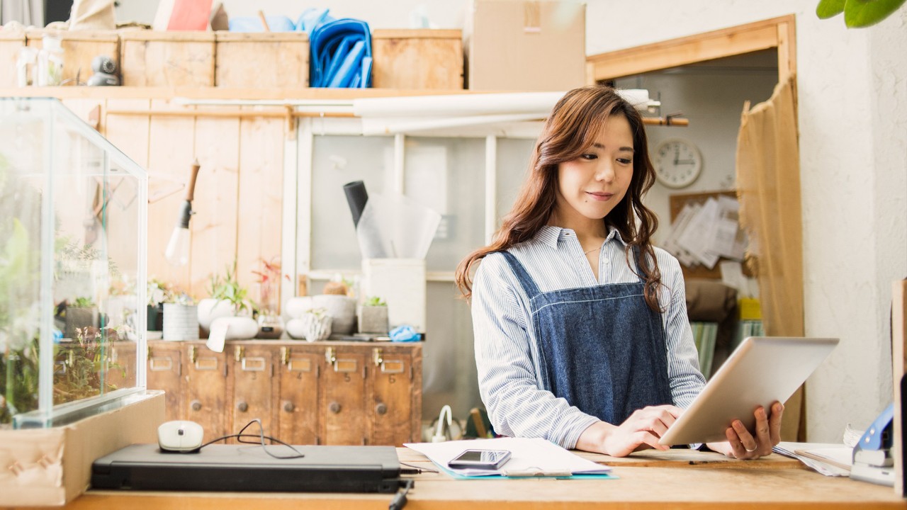 A woman is using tablet in the workshop; image used for "avoid excessive borrowing" article.