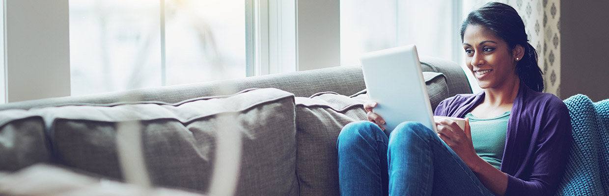 Happy woman using tablet on a couch; image used for HSBC Sri Lanka Ways to Bank