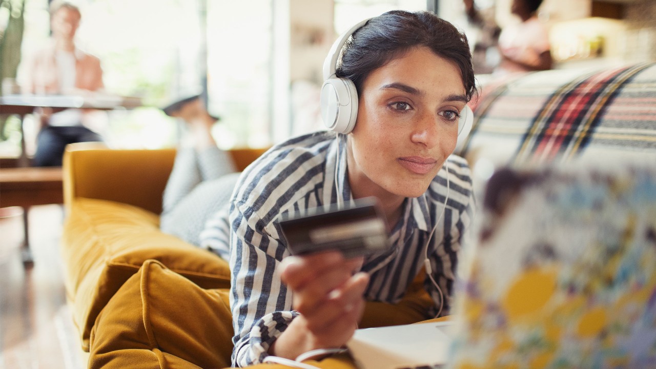 a woman lying on sofa with her credit card and laptop; image used for HSBC LK e-commerce credit cards offers page