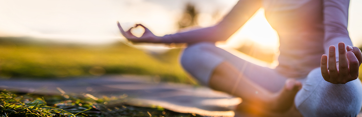 A woman wearing yoga outfit in Sukhasana pose on a lawn; image used for HSBC Sri Lanka credit card  health offer page